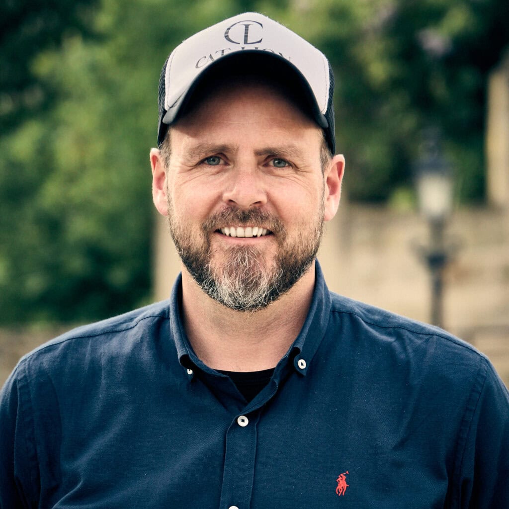 Mann mit Cap und blauer Hemd vor grünem Hintergrund, Marketingexperte.